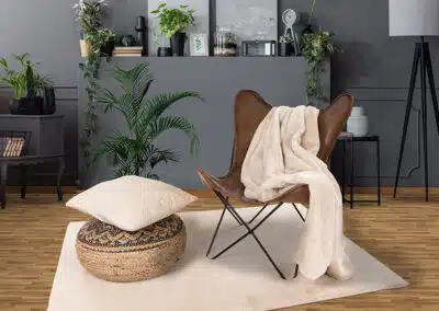 Beiger Teppich mit Decke und Kissen auf Stuhl
