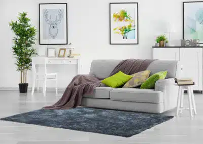 Pastellblauer Teppich vor grauem Sofa