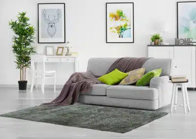 Pastellgrüner Teppich vor grauem Sofa